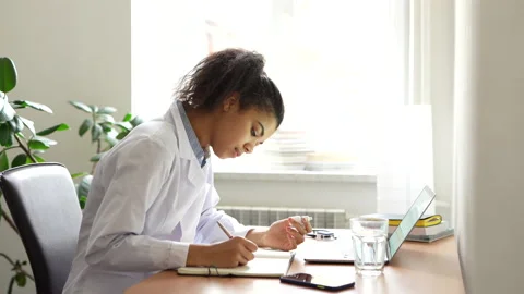 Researching and educating. Young mixed race woman, medical student making notes Stock Footage 145791459