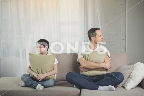 Resentful parent and child situating on couch Stock Photos