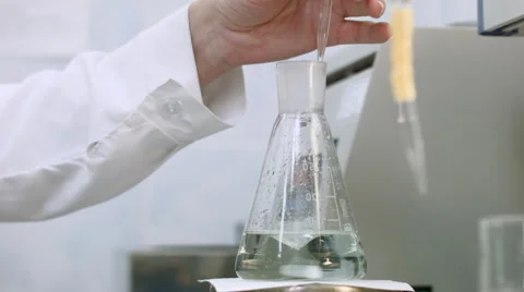 Resercher examining sample and mix green liquid in flask Stock-Footage 52030648