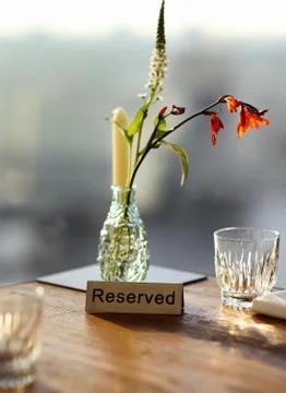 Reserved table in a cafe or restaurant with flowers in a vase and a candle. Foto stock