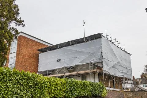 Residential Building Under Construction Covered with Protective Scaffolding and Stock Photos