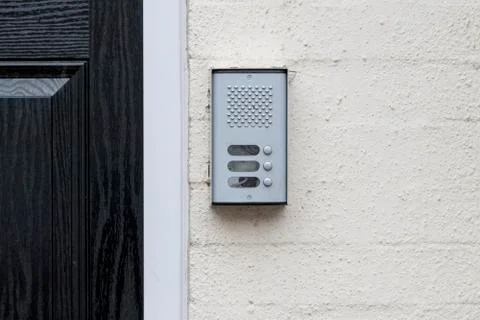 Residential buzzer intercom next to a black door on a white wall Stock Photos
