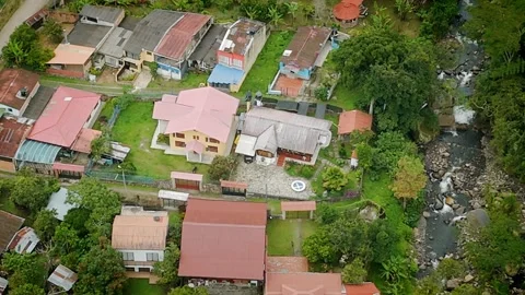 Residential compound with colorful rooftops bordering a flowing rural river Stock Footage 316790706