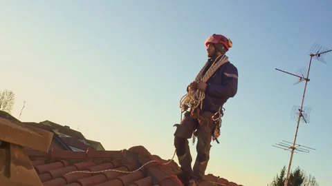 Residential rope access engineer with safety harness working on a roof Видео 125155352