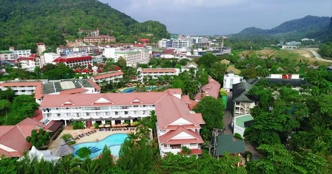 Resort blocks and swimming pools below a forested hill 库存影片 71297748