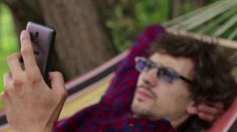 The resort in the hammock man using phone Stock Footage 64839721