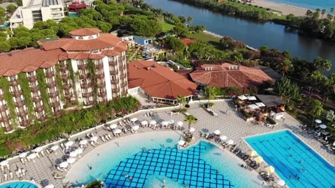 Resort hotel area with pool side, lounge bar, pine trees, river and braid beach Stock Footage 172362600