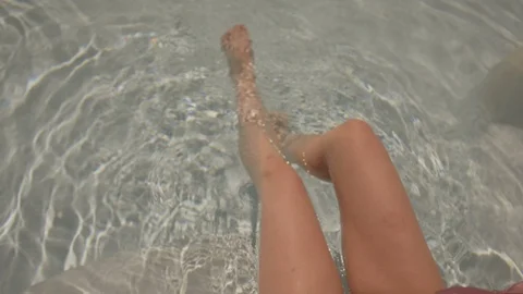 Resort Package 104 | Shot from back close up of woman legs playing in water Stock Footage 118459813