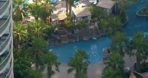 Resort pool with palm trees and waterfall from above 스톡 동영상 340478489