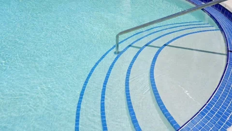 Resort swimming pool with four steps and steel railing decorated with blue and Video stock 247260554
