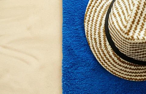 Resort theme background, texture. A hat on blue towel on a sandy beach. Stock Photos