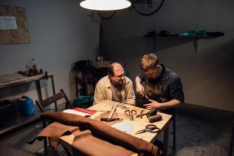 A respectable elderly shoemaker conducts a master class for a young boy on Stock Photos