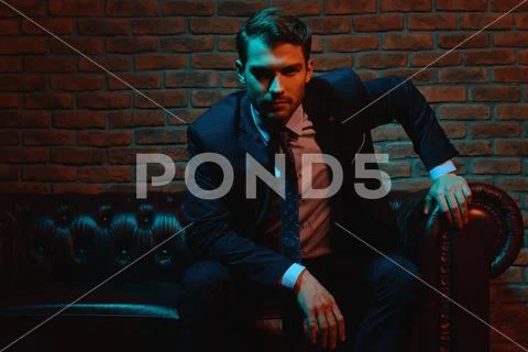 Respectable handsome man in elegant suit sitting in apartments with classical Stock Photos