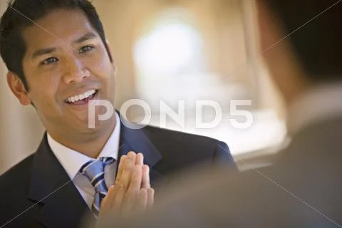 Respectful businessman greeting counterpart in building arcade, smiling (diff Stock Photos