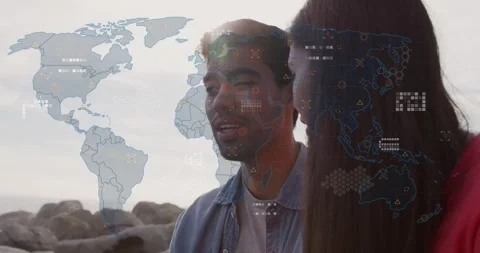 Responding to map overlay, man in denim shirt speaking at rocky shore, woman red Stock Footage 334185561
