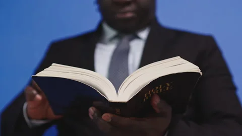 Responsible blackman scrolling through the holy bible pages Stockbeeldmateriaal 142565659