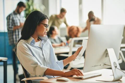 Responsible brunette lady checking data on paper at the office Stock Photos