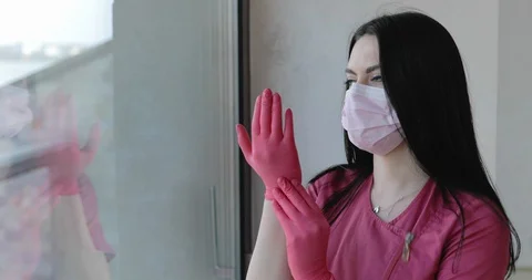 Responsible nurse corrects gloves before work and looking through the window Vídeo Stock 129426709