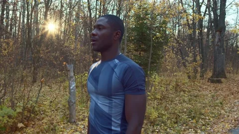Rest after a grueling workout. A dark-skinned man walks slowly next to the trees Stock Footage 163695415