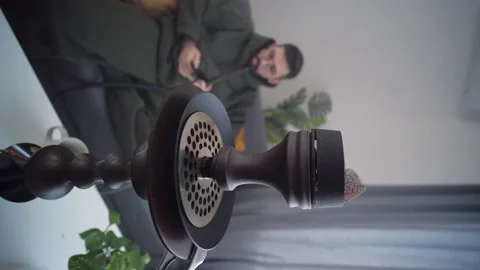Rest and relaxation concept. Man smokes a hookah in room of home interior Stock Footage 221653577
