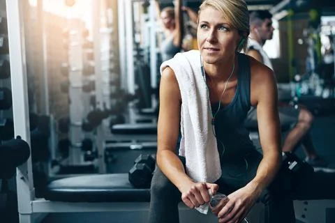 Rest, its part of the program. a young woman working out on her own in the gym. 스톡 사진