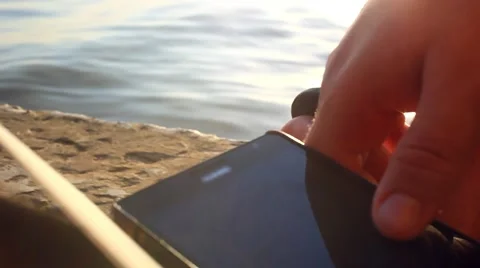 Rest man's hands uses mobile smartphone near the sea at sunset beach. With 스톡 동영상 51722949