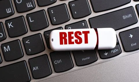 REST - the word on a white flash drive, lying on a black laptop keyboard Stock Photos