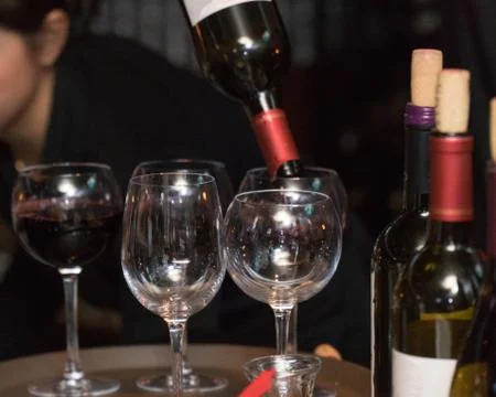 Restaurant bartender server pour bottle of wine into glass for customer drink Фото