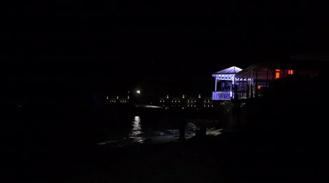 Restaurant at beach at night when moon path lighting on waves Stock Footage 68345386