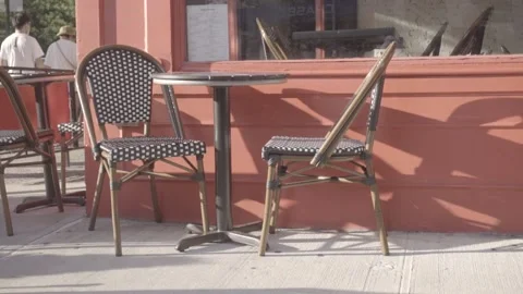 Restaurant chairs casting long shadows on red wall Stock Footage 157499215