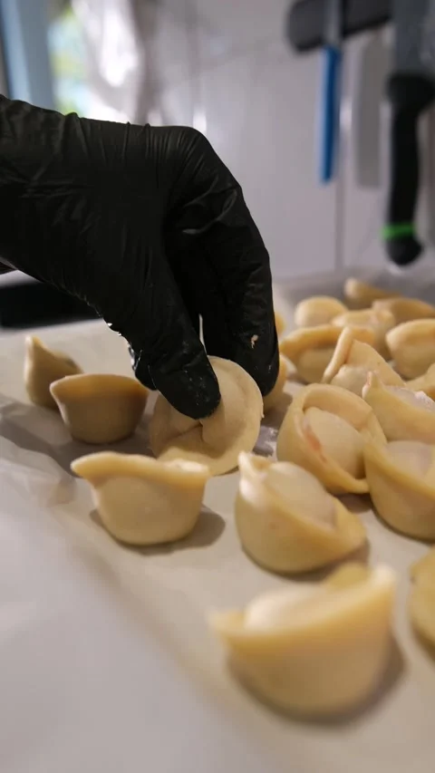 Restaurant chef in black gloves arranging freshly made raw tortellini on Stock Footage 318316897