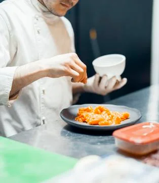 Restaurant Chef cook preparing salmon filet and salting it. Stock Photos