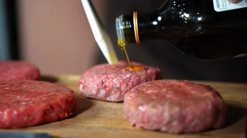 Restaurant chef in gloves oiling raw cutlets and sprinkling with fresh spices 스톡 동영상 108587001