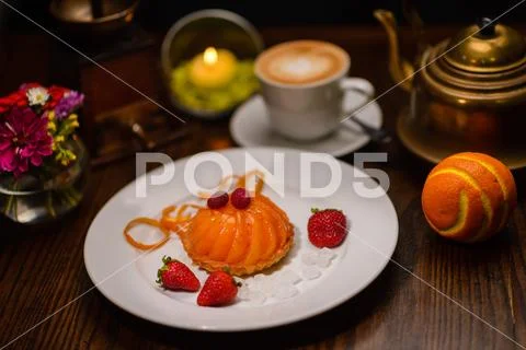 Restaurant cuisine, peach dessert with strawberries, near orange and cappuccino Stock Photos