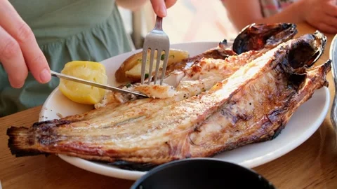 Restaurant customer eats grilled fish on a white plate Stock Footage 312012073