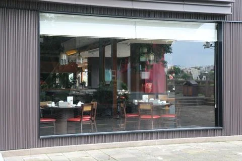 Restaurant dining room visible through a large glass window with set tables.. Foto stock