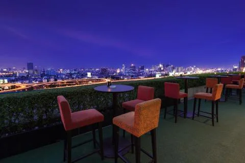 Restaurant dining table and view of business building on terrace at twilight  Stock Photos