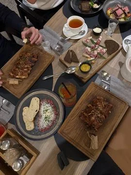 Restaurant Dinner Table with Pork Ribs, Beef Tartare and Sliced Pork Fat Stock Photos