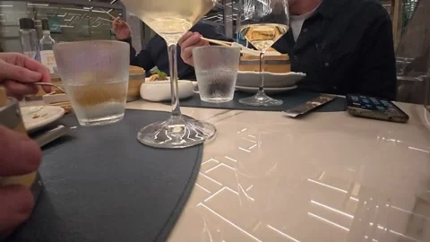 Restaurant dinner with wine glasses, water tumblers, plates and diners seated Stock Footage 346800339