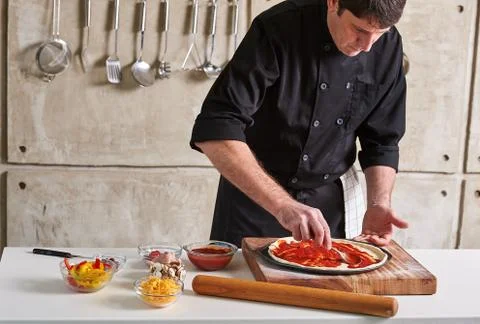 Restaurant hotel private chef preparing pizza adding toppings Stock Photos