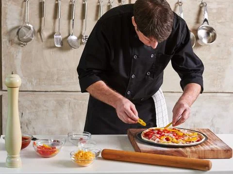 Restaurant hotel private chef preparing pizza adding toppings Stock Photos