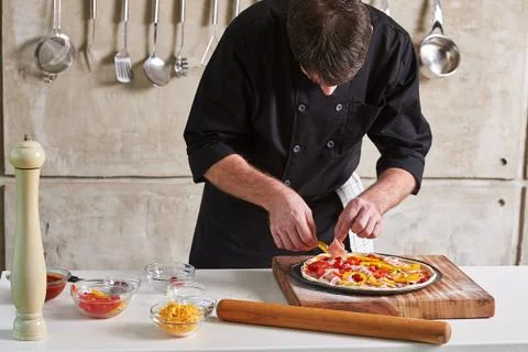 Restaurant hotel private chef preparing pizza adding toppings Stock Photos