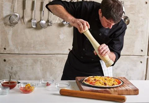 Restaurant hotel private chef preparing pizza adding toppings Stock-Fotos