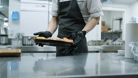 Restaurant kitchen. The chef gives the order a seafood dish to the waiter who 库存影片 106934238