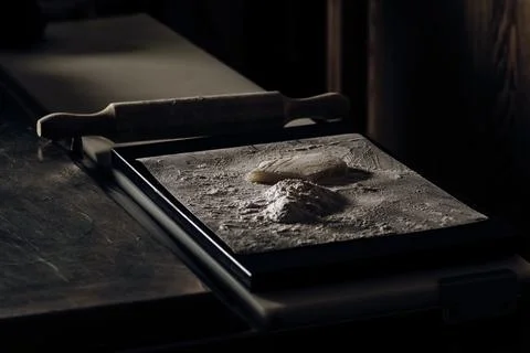 Restaurant kitchen table with a flour-filled tray, dough sprinkled with flo.. Stock Photos