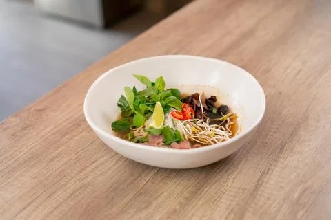 In a restaurant on light table a white plate with Japanese udon soup with meat Stock Photos