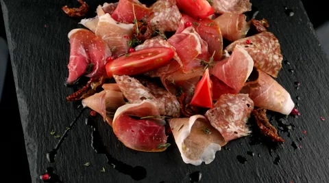 Restaurant meat platter (ham, salami, bacon) on the black stone tray Stock Footage 66481898