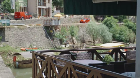 Restaurant or cafe table and chairs on sunny day in balcony overlooking river Stock Footage 284390298