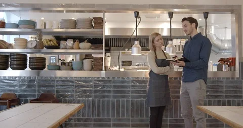 Restaurant owner talks to staff in kitchen of restaurant, small business, Stock Footage 128979863