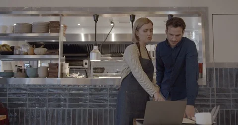 Restaurant owner talks to waitress in kitchen of restaurant, small business, Stock Footage 128979289